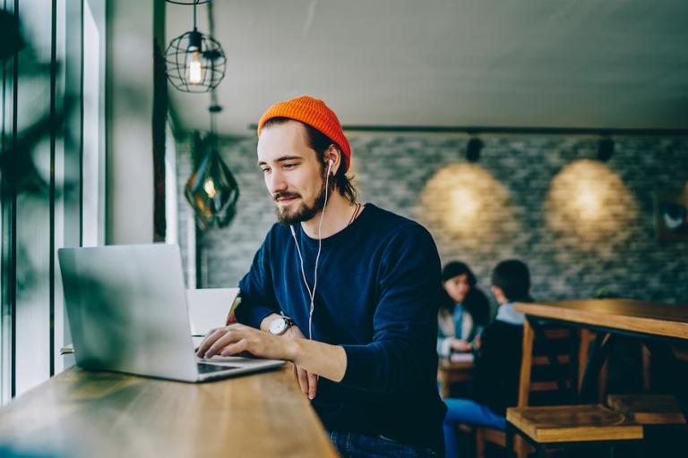 shutterstock_1469785070.jpg Web Developer working on work projects at a cafe